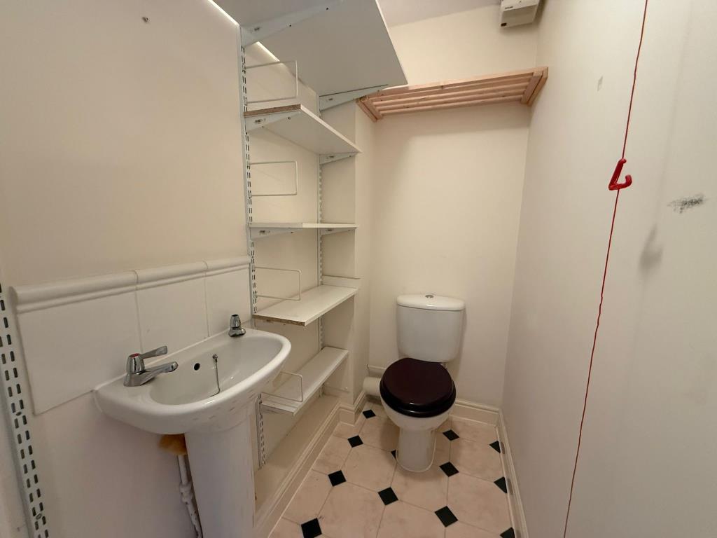 Lot: 50 - TWO-BEDROOM RETIREMENT FLAT IN NEED OF IMPROVEMENT - Toilet with storage shelves and hand basin